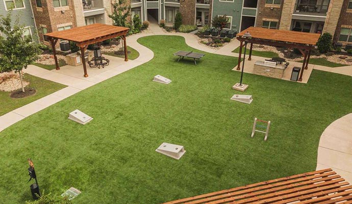 Apartment complex amenity lawn Apartment courtyard with artificial turf, cornhole, and grilling stations.