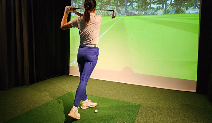 Woman playing golf in a golf simulator