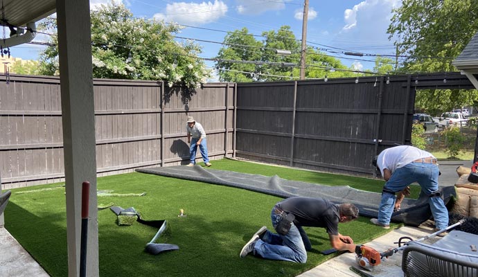 Professional turf installation Crew installing artificial turf in a backyard.