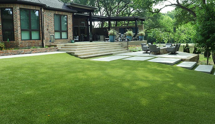Modern backyard with artificial turf High-end backyard with an artificial turf lawn and a large patio.