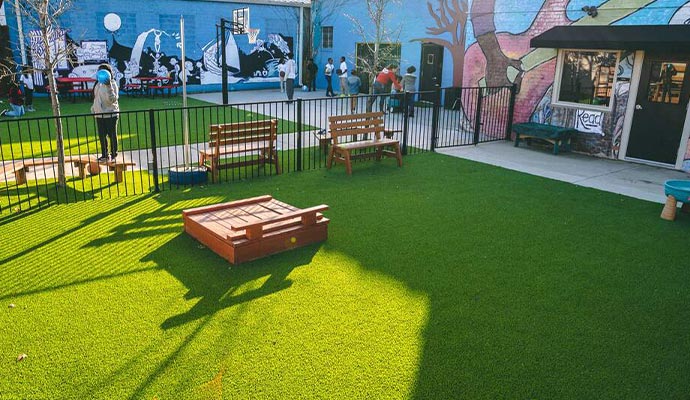 Urban community courtyard Urban play area with artificial turf, a sandbox, and colorful murals.